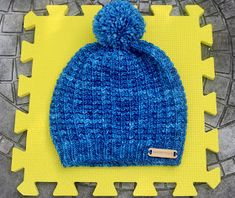 a blue knitted hat sitting on top of a piece of yellow foam with a tag