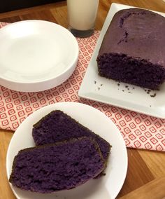 two slices of purple cake on plates next to a glass of milk and a plate