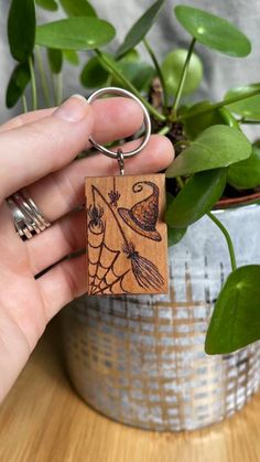 a hand holding a wooden keychain with a bird on it