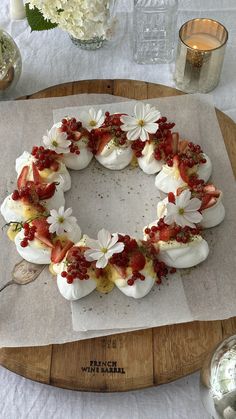 an arrangement of fruit and flowers arranged in the shape of a wreath on a wooden platter