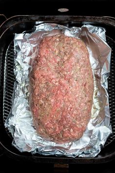 an uncooked meatloaf is sitting on tin foil in the oven, ready to be cooked