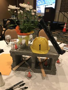 a construction themed centerpiece on a table in a conference room with flowers and candles