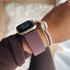 an apple watch on someone's wrist wearing a bracelet with white beads and a gold clasp