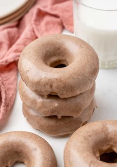 three doughnuts stacked on top of each other next to a glass of milk