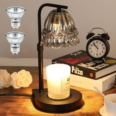 a table topped with a lamp next to a stack of books and an alarm clock