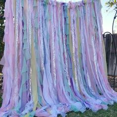 a large multicolored streamer hanging from a tree in front of a fence