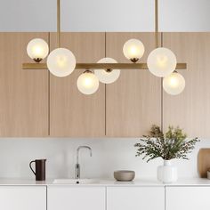 a kitchen area with a sink, counter top and hanging lights over it's cabinets