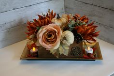 an arrangement of flowers and candles on a tray