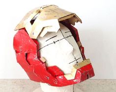 a paper mache head is shown on a white base with red and yellow paint