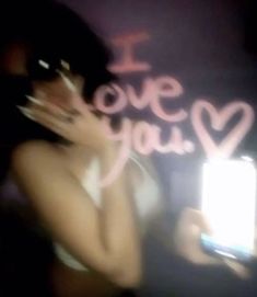 a woman holding a cell phone in her right hand and writing i love you on the screen