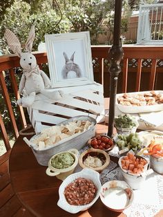 a wooden table topped with bowls filled with food next to a framed bunny on the wall