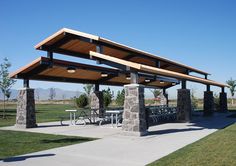 a covered picnic area in the middle of a field with tables and benches under it