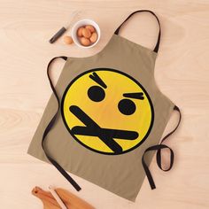 an apron with a smiley face drawn on it next to wooden spoons and utensils