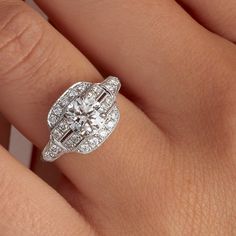 a woman's hand with a diamond engagement ring on her left hand and the center stone is surrounded by smaller diamonds