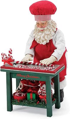 a santa clause figurine sitting on top of a table with candy canes