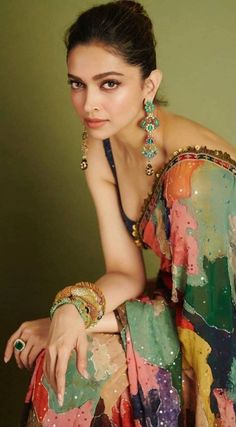 a woman in a colorful dress sitting on a chair with her hand on her hip