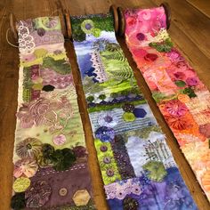 three pieces of colorful fabric sitting on top of a wooden table next to each other