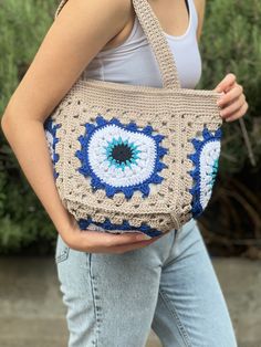 a woman carrying a crocheted bag with an eye on it