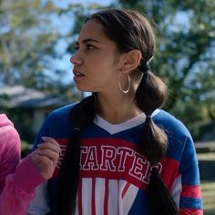 two young women standing next to each other in front of some trees and grass, one is wearing a sweater with the word farte on it