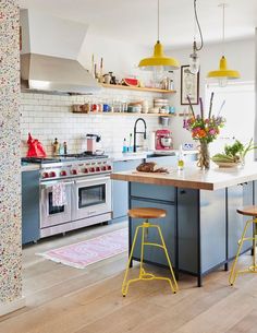 a kitchen with blue cabinets and yellow stools