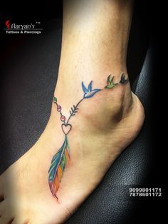 a foot with a colorful tattoo on it and a bird holding a bead in the shape of a heart