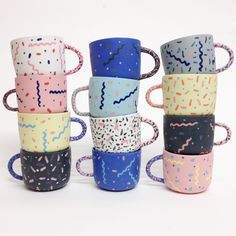 six different colored coffee cups with sprinkles on them