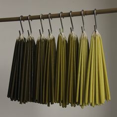 several yellow and brown umbrellas hanging from a wooden rack with metal hooks on it