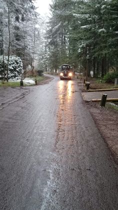 a car driving down a wet road in the middle of winter with snow on the ground