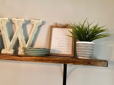 a wooden shelf with letters, plates and a potted plant sitting on top of it