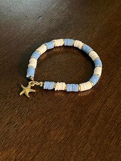 Blue and white bracelet with gold accents and a gold starfish Adjustable Blue Bracelets With Starfish Charm, Blue Bracelets With Starfish Charm Ocean-inspired, Blue Beaded Bracelet With Starfish Charm, Ocean-inspired Blue Starfish Bracelets, Casual Blue Jewelry With Starfish Charm, White Starfish Bracelet With Ocean-inspired Style, White Ocean-inspired Starfish Bracelets, White Starfish Ocean-inspired Bracelet, Ocean-inspired White Starfish Bracelet