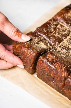 a person is touching the top of a loaf of brownies on a cutting board