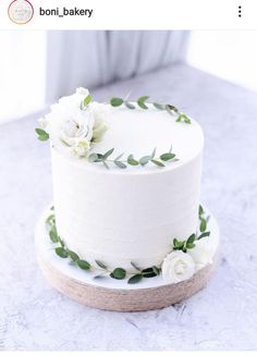 there is a white cake with flowers on the top and green leaves on the bottom