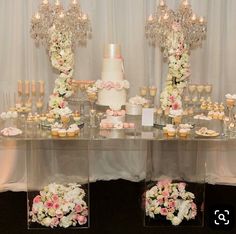 a table topped with lots of cupcakes covered in white frosting and pink flowers