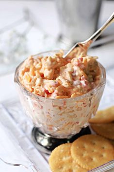 a glass bowl filled with food next to crackers