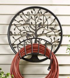 a tree is mounted on the side of a house with a hose rack attached to it