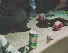 two skateboarders sitting next to each other with cans on the ground behind them