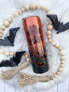 an orange and black tumbler sitting on top of a white rug next to wooden beads