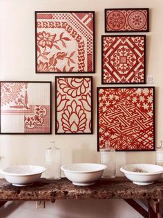 four bowls are sitting on a table in front of several framed art pieces, one is red and the other is white