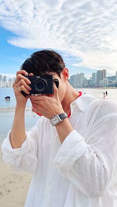 a man taking a photo with his camera on the beach in front of some buildings