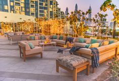 an outdoor seating area with couches, tables and lights on the side of it