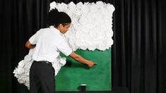 a young man is painting a large piece of art on a green and white wall