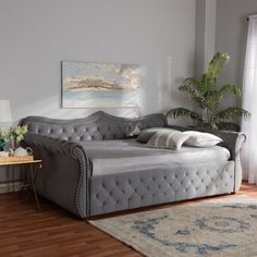 a gray daybed sitting on top of a hard wood floor next to a window