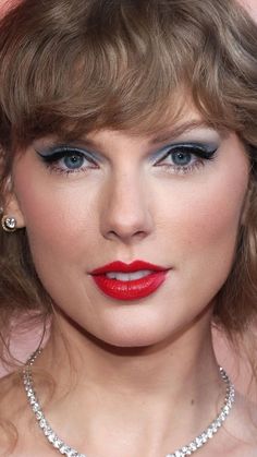 a close up of a person wearing a necklace and red lipstick with blue eyeshadow