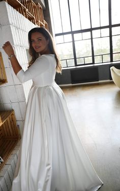 a woman in a long white dress standing next to a wall