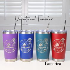 three different colored tumblers with straws in them on a table next to blinds