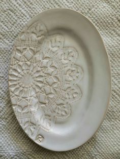 a white plate sitting on top of a table next to a cloth covered wallpaper