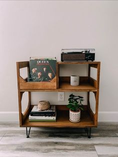 a wooden shelf with books and plants on it next to a wall mounted record player