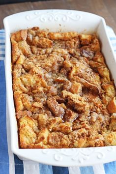 a casserole dish filled with bread and other toppings on a blue and white table cloth