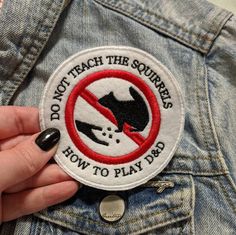 a person is holding a patch that says don't teach the squirrels how to play bass