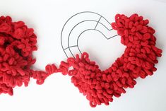 a pair of red knitted wreaths sitting on top of a white surface